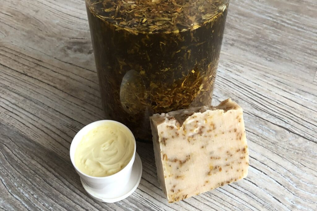 Körömvirág-macerátum üvegben, mellette kézzel készített kenőcs és szappan